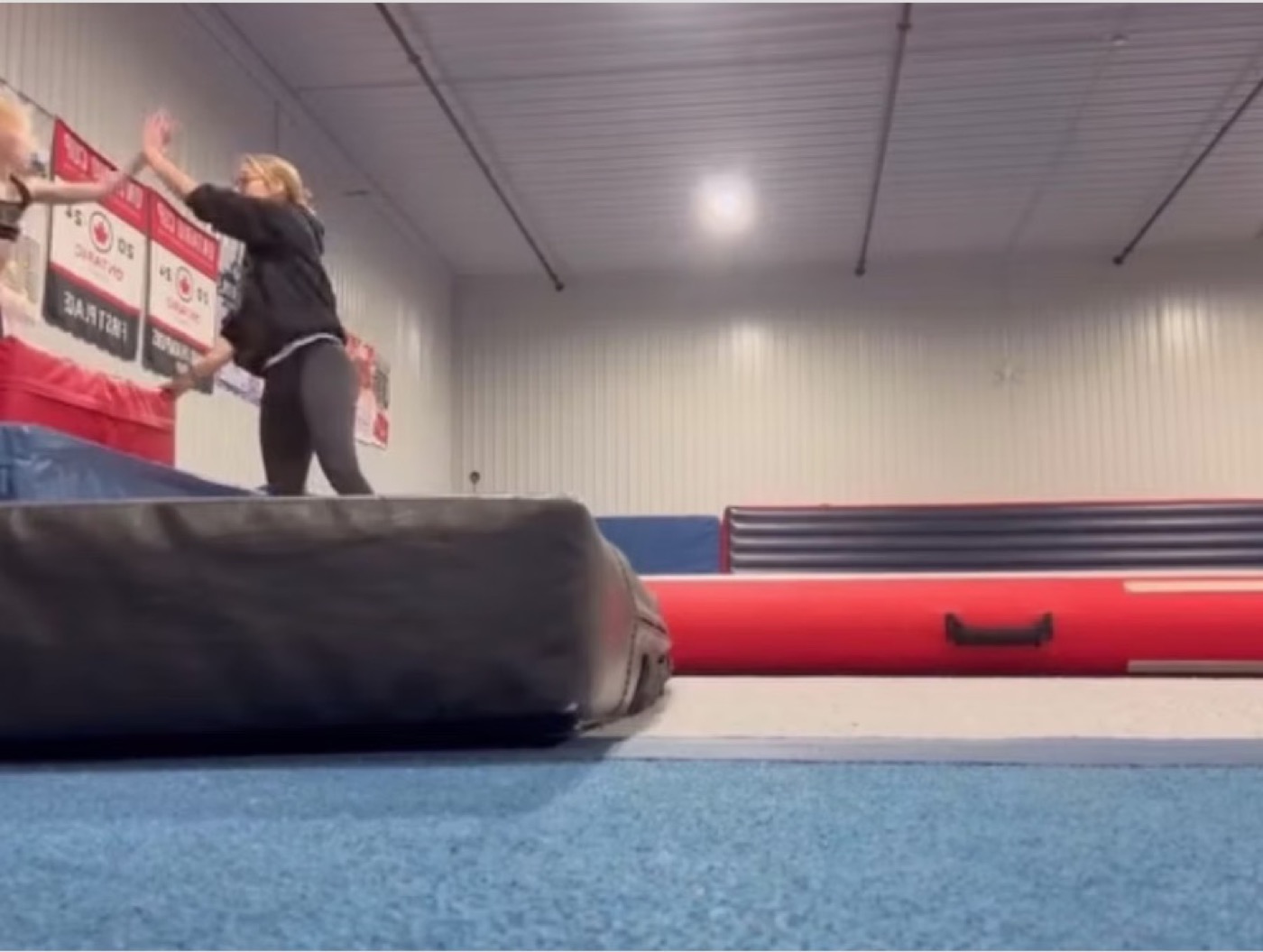 A CheerCore Jags coach spotting an athlete on a tumble track
